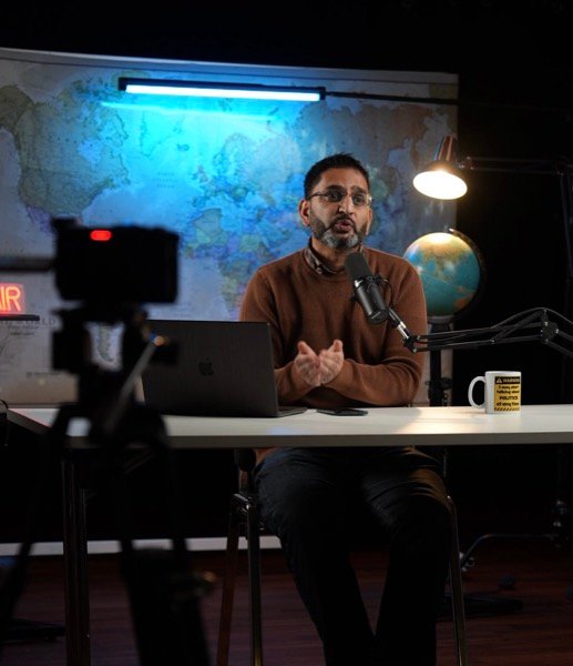 Filming podcast-style interview in cinematic studio setup with world map backdrop